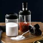 Transparent glass jar with built-in spoon for easy kitchen access to spices