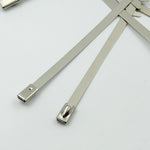 Durable stainless steel cable tie securing electrical wiring in an industrial setting.