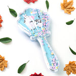 Back view of the kids' detangling hair brush, showcasing the unique cartoon design and paddle shape.