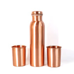 A person pouring water from the leakproof copper bottle into one of the matching glasses.