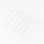 Stack of 6 white plastic clothes hangers ready for use
