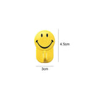 Smiley face wall hooks holding various items, showcasing their 1 kg load capacity.