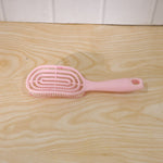 Woman brushing her hair with pink curved styling brush