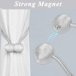 A pair of elegant silver magnetic curtain tiebacks arranged decoratively.